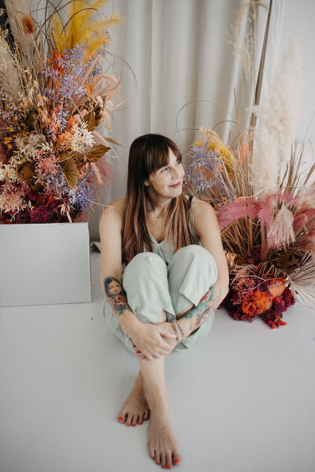 Katrin Seelenbalm – achtsame Yogalehrerin zwischen Blumenarrangements, Symbol für Ruhe und Bewusstsein